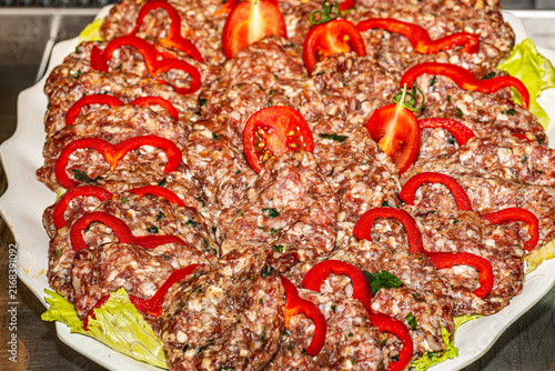 Traditional grilled Turkish köfte meatballs served hot on a plate with grilled peppers, onions, and fresh parsley. Authentic Middle Eastern cuisine.