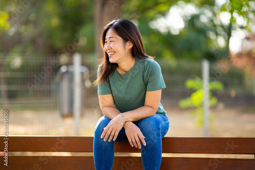 Asian woman sitting on bench enjoying peaceful moment