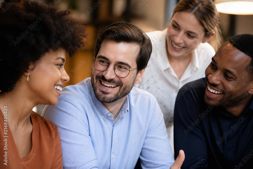 Fototapeta premium Four smiling adults are gathered together in an indoor setting, engaged in friendly conversation.