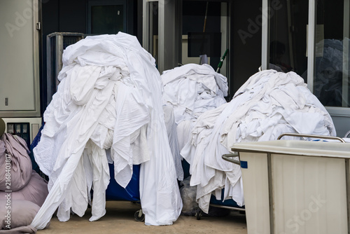 Foto Heap of Laundry: A pile of white linens, likely bedding or towels, sits in piles on trolleys, awaiting washing or folding