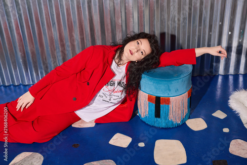 Fotografie Expressive woman in red reaches toward stones with artistic flair
