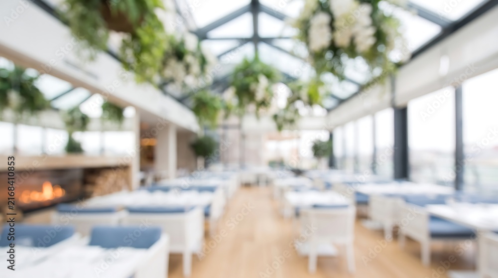 Fototapeta premium Blurred interior view of a modern high end restaurant with hanging plants and large windows creating a bright and airy dining atmosphere for a sophisticated culinary experience