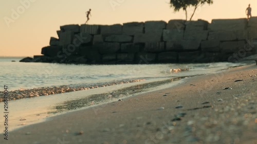 Calm evening sea surf, someone running in the background in defocus