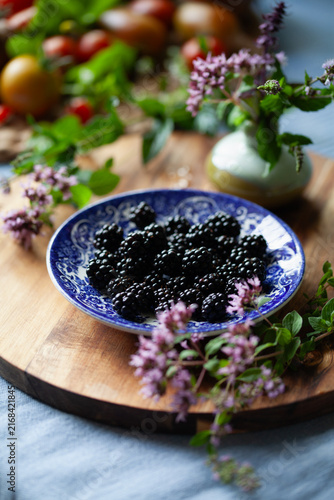 Alpine starwberry  - Fragaria vesca and blackberry fruit on a vintage English plate with fresh herbs -  soft fruit garden treat.