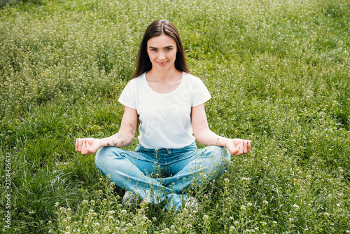 Fotografie Young woman meditating outdoors in a grassy field, practicing mindfulness and re