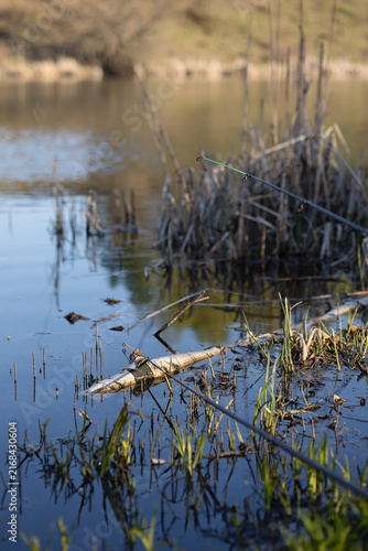 A photo of a fishing rod on the shore of a reservoir.