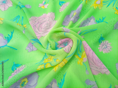 Floral pattern swirled features a variety of flowers, including roses, daffodils, and other blossoms in shades of pink, purple, and yellow, scattered across a bright green background.