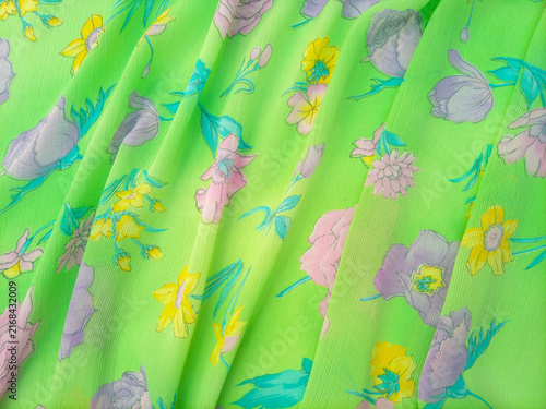 Layered Floral pattern features a variety of flowers, including roses, daffodils, and other blossoms in shades of pink, purple, and yellow, scattered across a bright green background