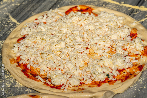 Professional chef kneading and stretching fresh pizza dough with flour in a restaurant kitchen. Authentic Italian pizzeria cooking process.