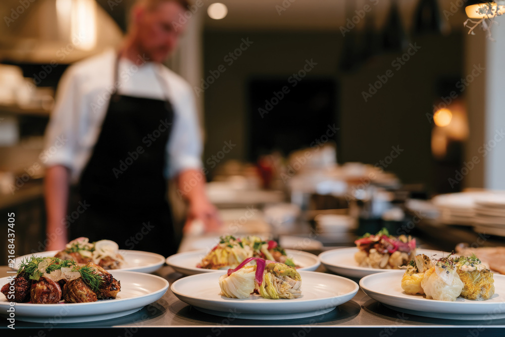 Obraz premium A skilled chef artfully prepares gourmet plates in a modern restaurant kitchen, embodying culinary mastery and the passion for creating exquisite dining experiences.
