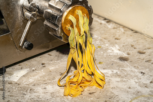 Freshly made artisanal tagliatelle pasta nests dusted with flour on a rustic wooden board. Raw homemade Italian fettuccine.