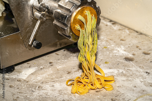 Freshly made artisanal tagliatelle pasta nests dusted with flour on a rustic wooden board. Raw homemade Italian fettuccine.
