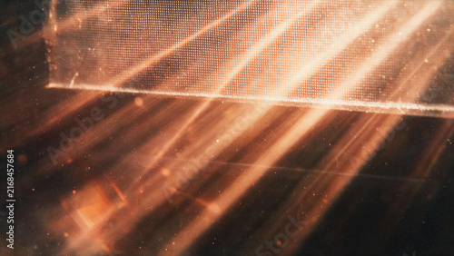 Abstract cinematic light rays with floating dust particles, light leak effect and screen texture on a dark background.