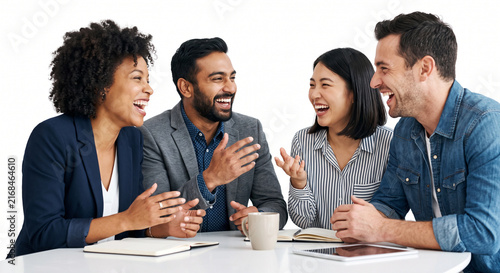 Group of four happy diverse multiracial colleagues sitting around meeting table talking and laughing