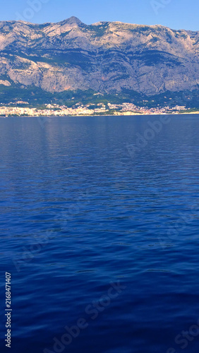 A serene adriatic sea view captures the tranquil coastline, perfect for summer vacation travel. The calm waters and distant mountains invite tourists to explore this picturesque beach destination.