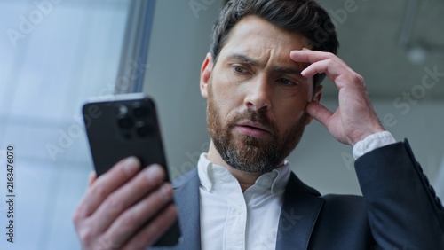 Фотография Upset Caucasian middle-aged business man receive bad notification with mobile phone in office