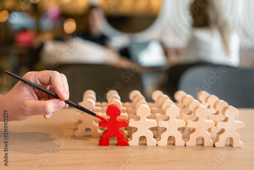 Photography Talent recruitment and leadership concept with hand painting wooden figure in red among crowd on table for employee selection, career training, standout candidate and business development