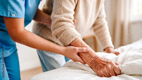 Infirmière aidant une patiente a s'appuyer su son lit