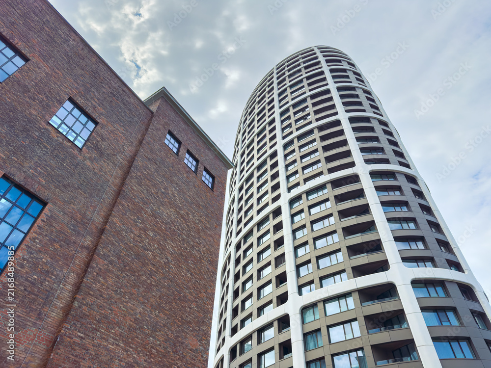 Fototapeta premium Modern building next to brick structure during cloudy day in an urban area