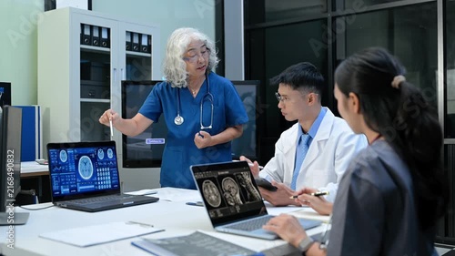 Senior doctor explains MRI brain scan results to a diverse medical team in a high tech hospital