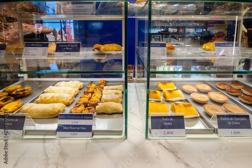 Cascais, Portugal - 22 August 2026: View of a bakery display case filled with traditional Portuguese pastries including Travesseiro de Sintra and Pastel de Nata.