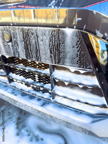 Fotografie Car getting washed with soapy water on a sunny day in a car wash location