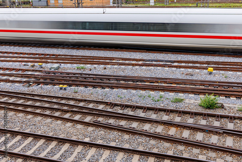High angle view of motion blurred white high speed train passing over multiple railway tracks, rail transport and infrastructure concept