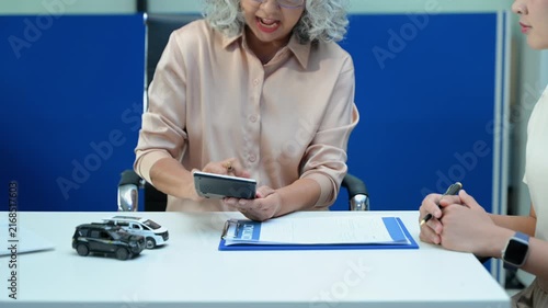 Car insurance consultation using smartphone and documents. Advisor and customer reviewing digital insurance service, auto policy, finance
