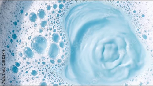 Close up of swirling blue liquid with foam and bubbles.