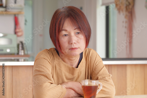 Tapety artystyczne 疲れた表情でテーブルに座るミドル女性