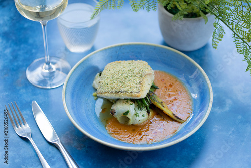 Photography Delicious Fish Dish Served With Creamy Sauce on a Vibrant Blue Table