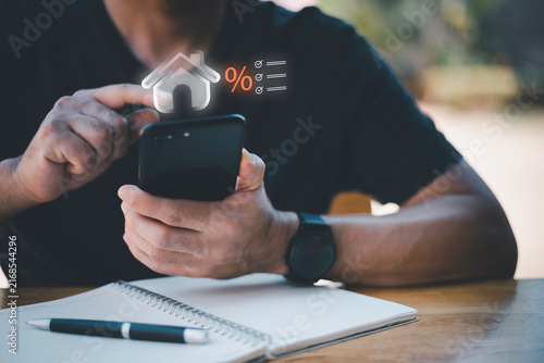 Businessman using telephone and laptop with house interest rate icon. Concept of real estate tax, mortgage loan calculation, financial planning, and home property investment.