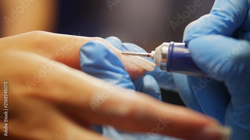 Professional manicurist cleaning client nails with electric nail drill during manicure procedure in beauty salon focused on healthy nails and elegant appearance. High quality 4k footage