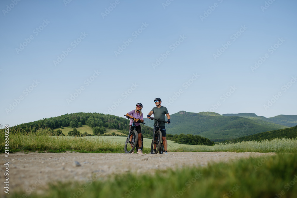 Fototapeta premium Senior couple taking break during e-bike ride, enjoying nature around them.