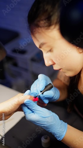 Professional manicurist applying nail polish on female nails during beauty salon procedure focused on elegant appearance self care and healthy nail care routine. High quality 4k footage