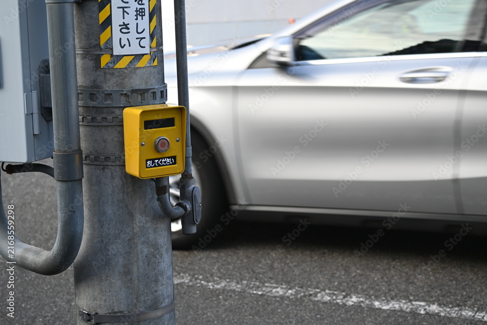 Fototapeta premium 押しボタンの前を通り過ぎるシルバーの自動車