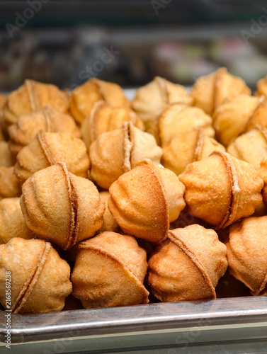 Walnut shaped pastries filled with boiled condensed milk stand in a confectionery display case, offering an appealing dessert selection with a rich sweet filling