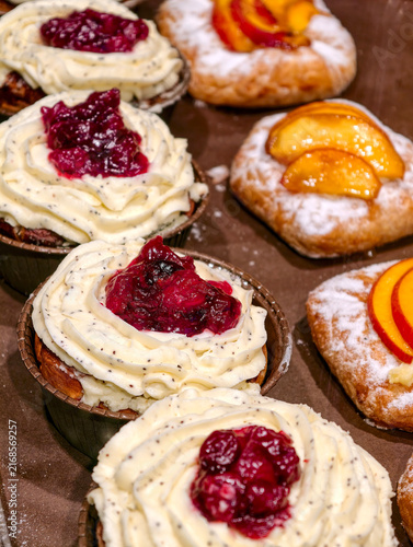 Fresh cream pastries with cherry filling displayed in a bakery showcase, highlighting sweet baked products presented attractively for customers and shoppers