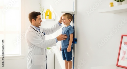 Doctor measuring child's height using stadiometer in a bright, modern clinic examination room, promoting healthcare and growth monitoring.