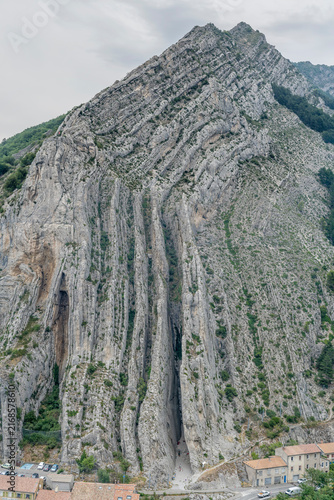 Rocher de La Baume tall cliffs of layered rock on Durance river shore, Sisteron, France