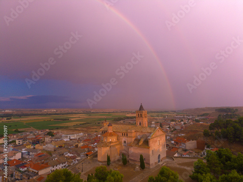 Bild auf Leinwand arco iris e iglesia en pueblo al atardecer