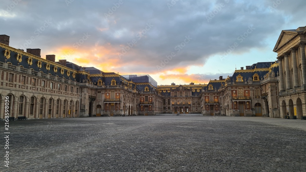 Obraz premium La Cour royale du château de Versailles vue depuis le Grand Portail au coucher du soleil (France)
