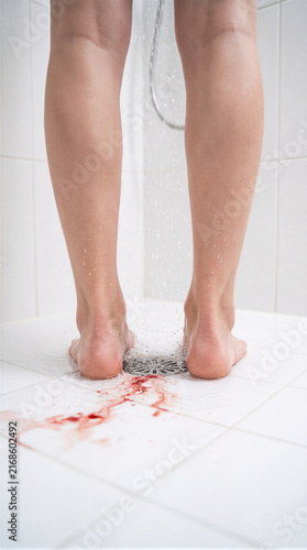 Woman's legs in a shower with blood draining conceptualizing domestic violence, abuse, and physical assault