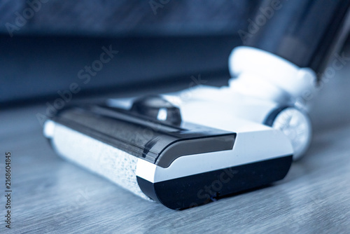 Vacuum cleaner being used on wooden floor to clean dust and dirt in a living room