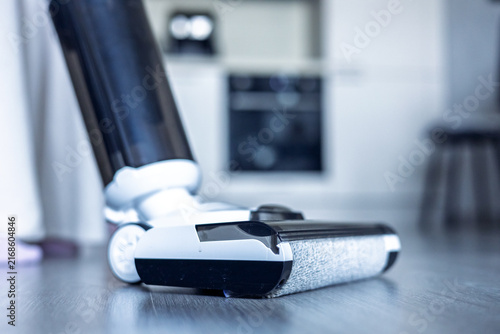 Vacuum cleaner on wooden floor near kitchen appliances in a home setting