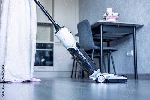 Cleaning the floor with a vacuum cleaner in a modern kitchen area during daytime