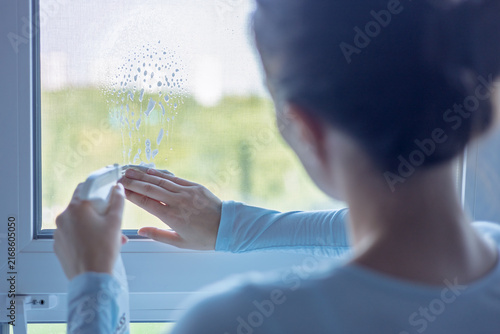 Woman cleaning window at home during daytime