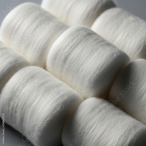 Close up of sterile white cotton rolls arranged neatly, showcasing soft fluffy fibers for medical and craft applications