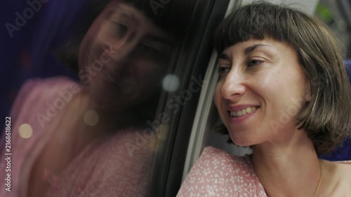 A young woman returns from working on the train at night. Her face is reflected in the train window as she drives through the metropolis. The passenger of the train. girl on the train. 
