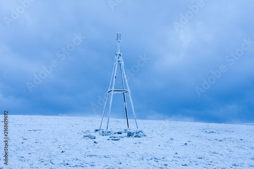 Konstfotografi Icy triangulation tower stands alone on a snow-covered mountain peak